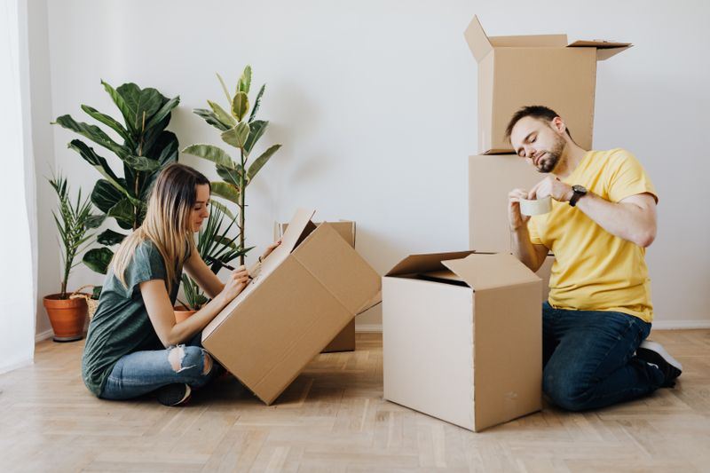 Couple packing their belongings into boxes on the floor at home