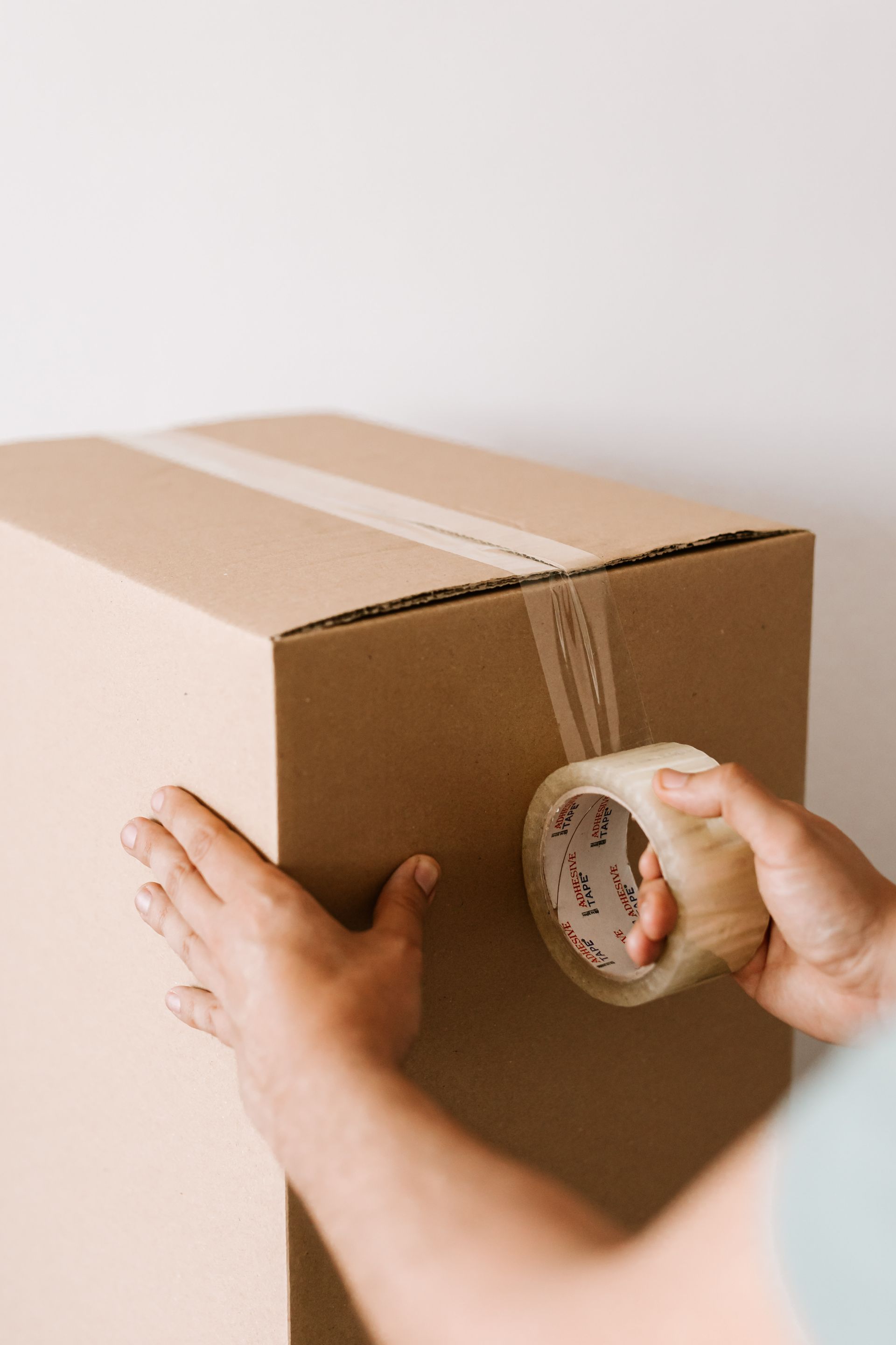Professional sealing a packed cardboard box with tape
